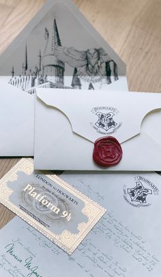 two envelopes with wax stamp on them sitting next to an envelope and some other items