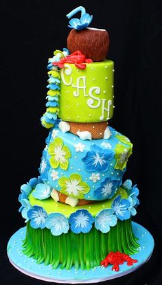 a three tiered cake is decorated with blue and green frosting, flowers, and leaves