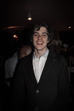 a smiling young man in a black jacket and white shirt