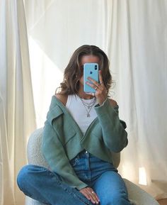 a woman is taking a selfie with her cell phone while sitting on a chair