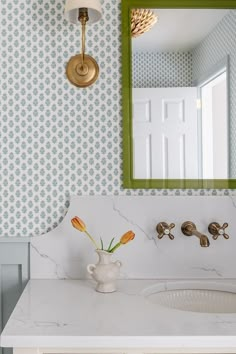 a white sink sitting under a green framed mirror