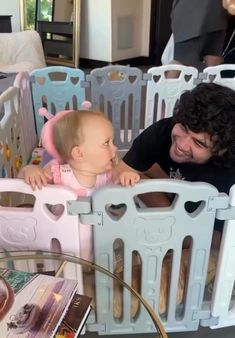 a man is smiling at a baby in a crib