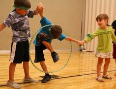 three young children playing with a hula hoop