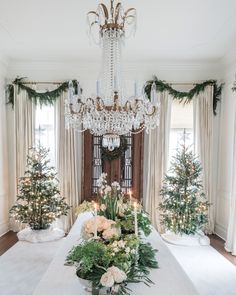 an elegant dining room decorated for christmas with greenery and candlesticks on the table