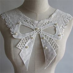 a white mannequin with an intricate bow on it's back and neck