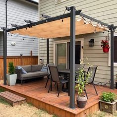 a patio covered in furniture and lights next to a house with a deck that has a couch on it