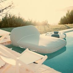 a lounge chair sitting on top of a swimming pool next to a lush green field