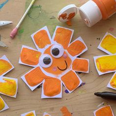 an orange paper flower with googly eyes surrounded by crafting supplies on a table