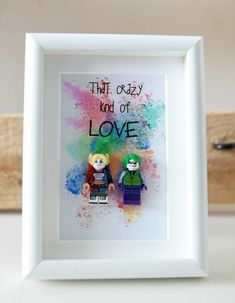 two legos are sitting in front of a frame with the words that crazy kid of love written on it