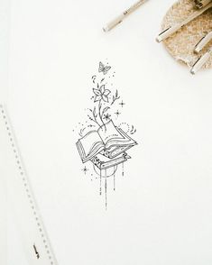 an open book sitting on top of a table next to some pens and pencils