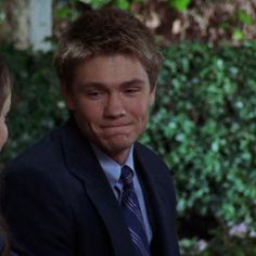 a young man in a suit and tie standing next to a woman