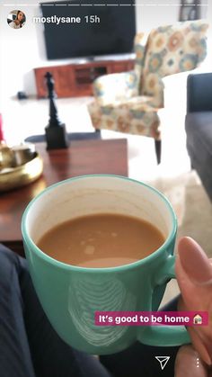 a person holding a cup of coffee in front of a couch with the caption it's good to be home