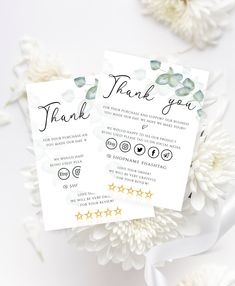 two wedding thank cards sitting on top of white chrysant flowers with gold stars