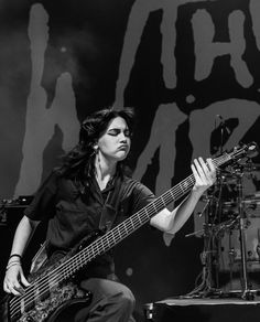 a woman playing a bass guitar on stage