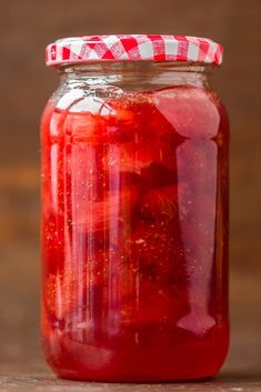 a jar filled with red liquid sitting on top of a wooden table