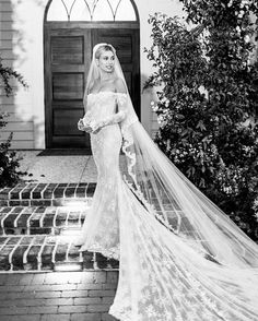 a woman in a wedding dress is standing on the steps with her veil over her head