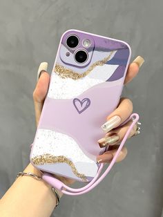 a woman holding up her phone case with gold glitters and hearts on the back