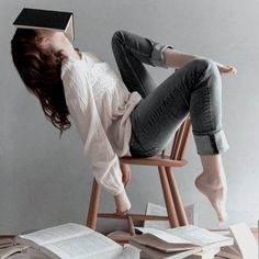 a woman is sitting on a chair with books in front of her head and she's upside down