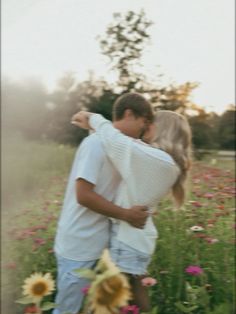 a man and woman embracing in a field with sunflowers