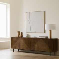 a wooden sideboard with two vases on it in front of a large window