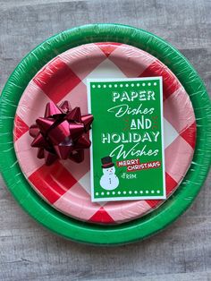 a paper plate with a holiday card and bow on it next to a christmas ornament