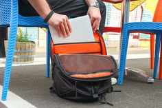 a man sitting in a chair with an orange and black backpack