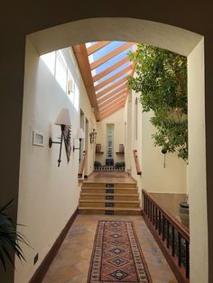 an entry way with stairs, potted plants and a rug on the floor in front of it