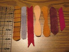 five different colored ties are lined up next to a measuring ruler on a wooden table