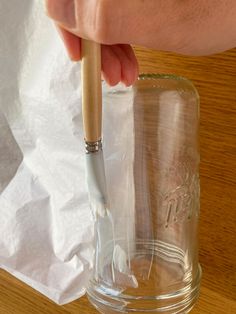 a person is holding a brush in a mason jar