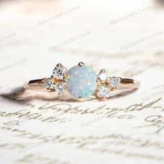 an opal and diamond ring sitting on top of a piece of paper