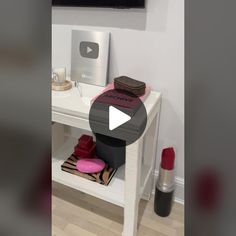 a white table topped with lipstick next to a wall mounted flat screen tv on top of a wooden floor