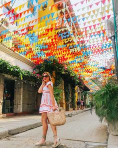 a woman is walking down the street in front of colorful flags hanging from the ceiling