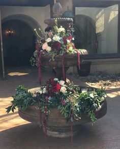 a water fountain decorated with flowers and greenery