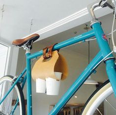 a blue bicycle with two cups hanging from it's handlebars in a room