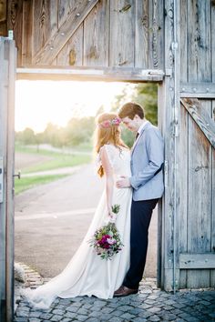 a bride and groom kissing in front of an open barn door