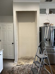 a kitchen that is being remodeled with a ladder in the foreground and a refrigerator in the background