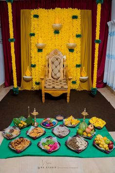 a table topped with lots of food next to a yellow wall covered in flowers and greenery