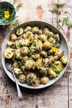 a bowl filled with potatoes and herbs on top of a wooden table