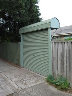 a closed garage door on the side of a wooden fence