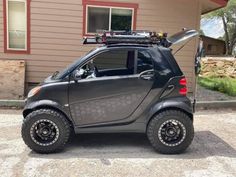 a small car parked in front of a house with skis on it's roof