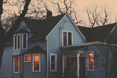 a blue house with trees in the background at sunset or dawn, on a street corner