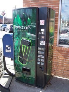 a monster energy drink vending machine on the sidewalk