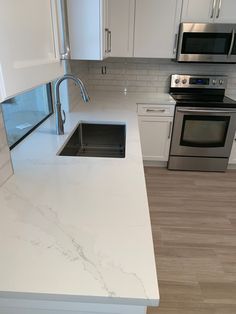 a kitchen with white marble counter tops and stainless steel appliances