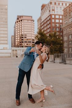 a man and woman kissing while holding wine glasses