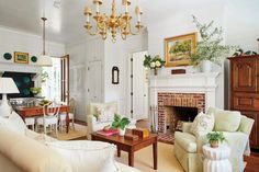 a living room filled with furniture and a fire place under a chandelier hanging from the ceiling