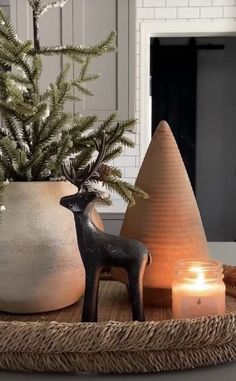 a candle is sitting on a tray next to a potted plant and a deer figurine