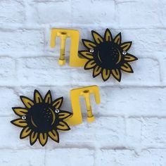 two black and yellow sunflowers are on the wall next to each other in front of a white brick wall