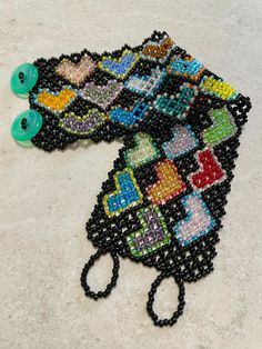 "This cuff-style bracelet is made of size 11/0 seed beads, opaque black with hearts in various colors.  Closure is 2 small buttons (green) and bead loops. Bracelet is 1 3/4\" wide. Size: 6 3/4\" (band is 6 1/4\", clasp adds 1/2\".) I recommend measuring your wrist and adding 1/2\" for best fit." Black Beaded Bracelets With Heart Beads As Gift, Black Beaded Bracelets With Heart Beads For Gifts, Black Beaded Bracelets With Heart Beads For Friendship, Black Beaded Bracelets With Heart Beads, Handmade Green Heart Beaded Bracelets, Black Heart Bead Bracelet For Friendship, Black Heart Beads Bracelet For Friendship, Adjustable Multicolor Beaded Heart Bracelet, Black Beaded Heart Bracelets With Heart Beads