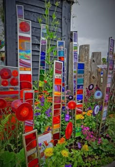 a garden filled with lots of colorful flowers and art pieces on the side of a building