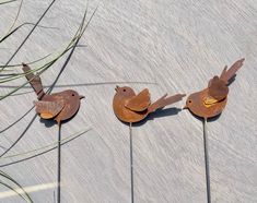 three metal birds sitting on top of each other in front of some grass and rocks